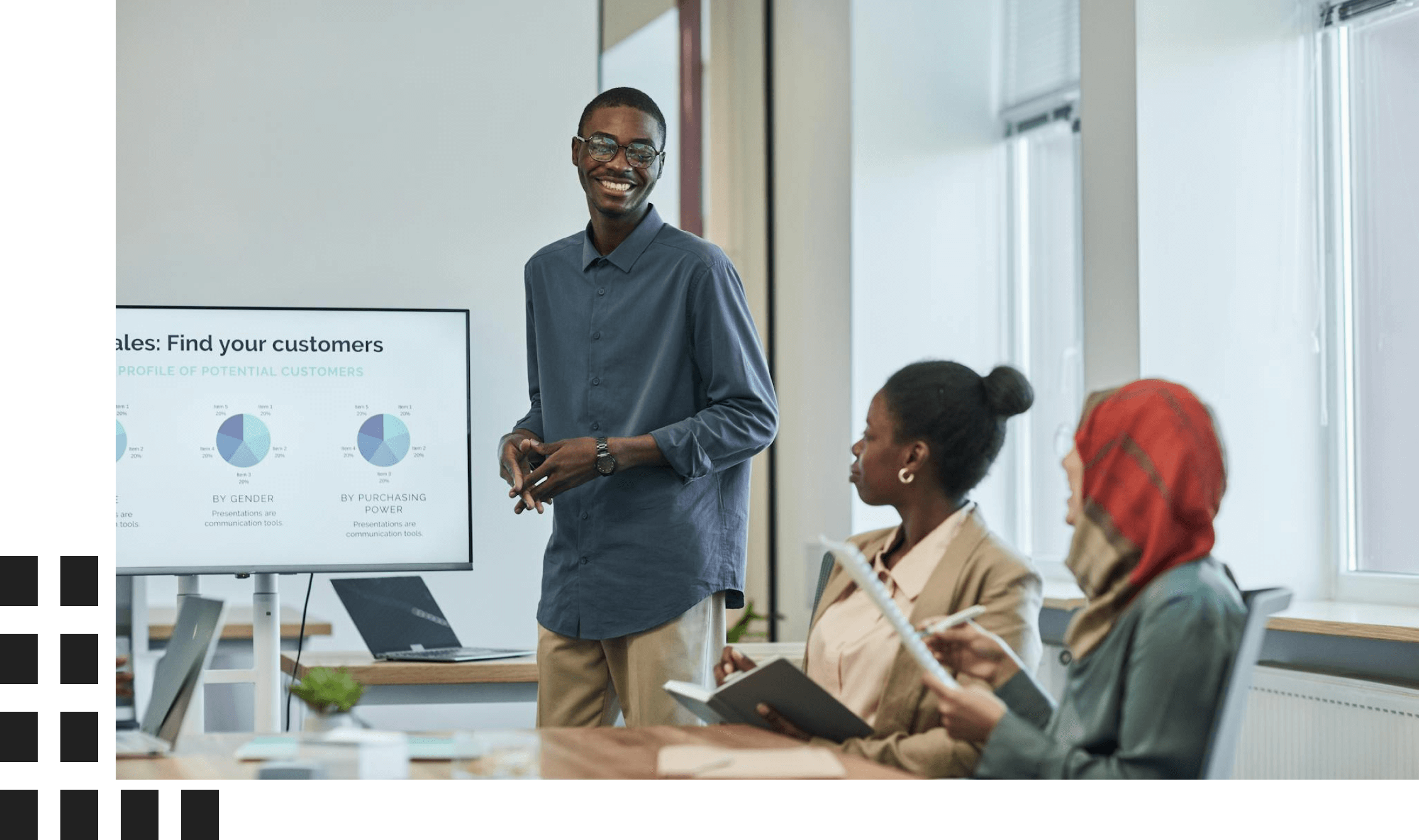 Man presenting data to colleagues in a meeting room with charts on a screen